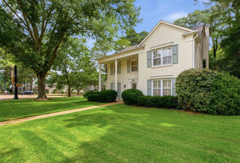 Traditional two-story exterior with light-toned brick, a columned entryway, and contrasting light blue shutters