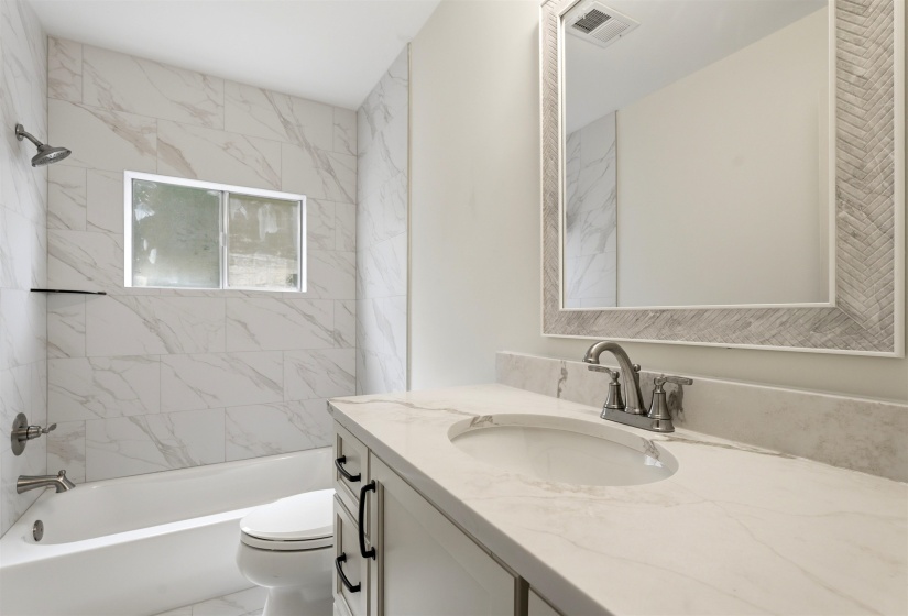 Bathroom featuring a white vanity with a light-toned countertop, an integrated sink, and a framed mirror