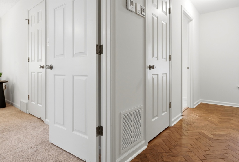 Hallway featuring paneled doors, white baseboards, and wood-finish herringbone flooring