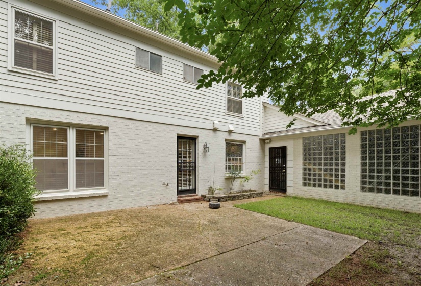 Exterior patio and lawn area featuring a painted brick and siding facade