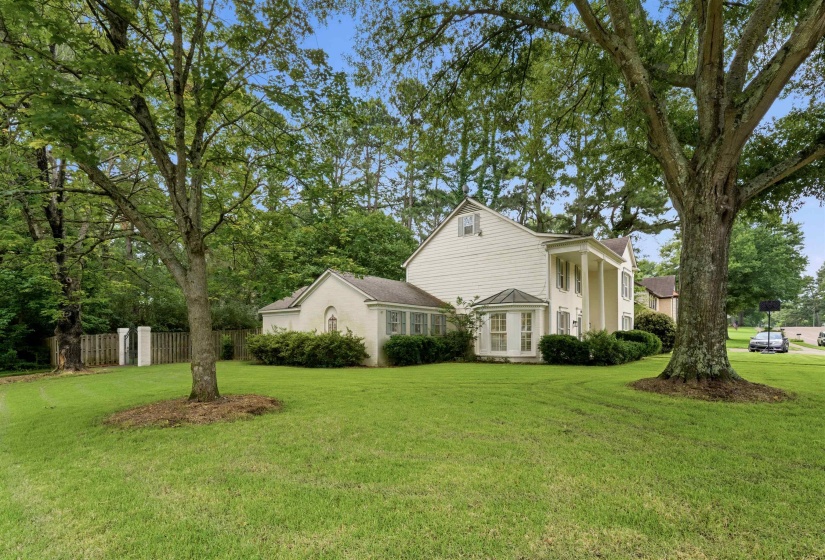 Expansive green lawn surrounds a traditional-style residence with white siding and a prominent columned entrance