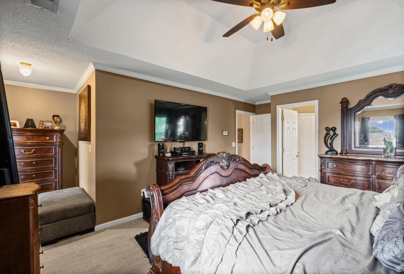 Vaulted ceiling with a ceiling fan, crown molding, neutral paint, and carpeted flooring