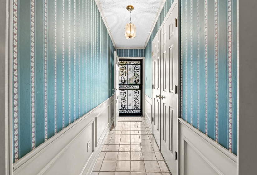Entryway featuring wainscoting, patterned wallpaper, a decorative security screen door, and a flush-mount ceiling light fixture