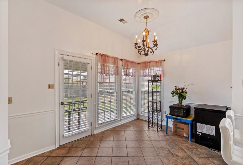 Dining space with lofted ceiling, tile patterned flooring, and a chandelier