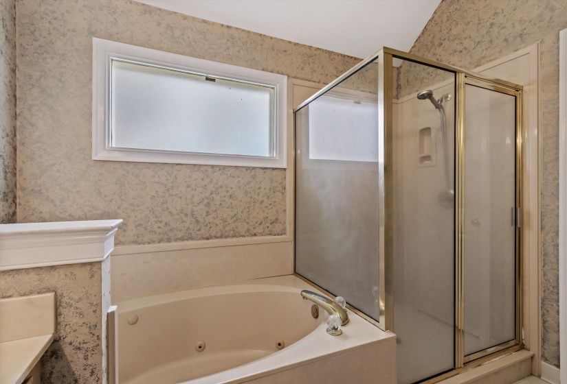 Full bathroom featuring wallpapered walls, a stall shower, vanity, and a tub with jets