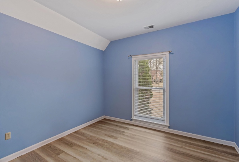 Spare room featuring light wood-style flooring and vaulted ceiling