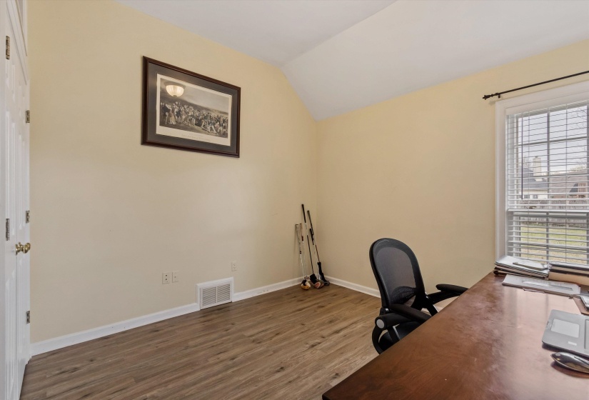 Unfurnished office featuring wood finished floors and vaulted ceiling