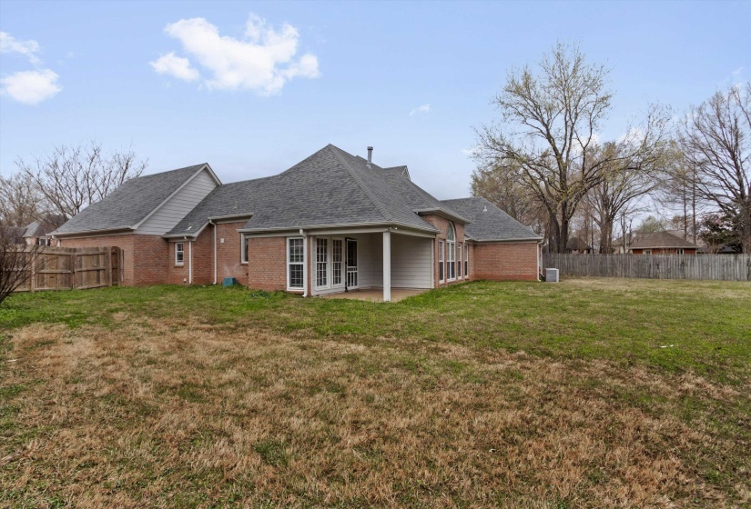 Rear view of property featuring a fenced backyard, brick siding, a patio area, and roof with shingles