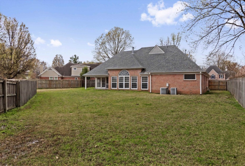 Back of property featuring brick siding, a shingled roof, and a fenced backyard