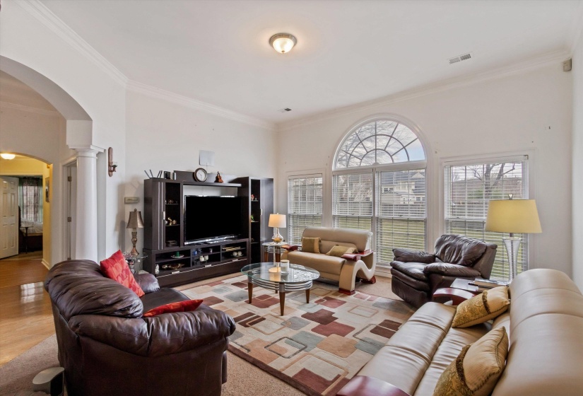 Living area with arched walkways, crown molding, and ornate columns