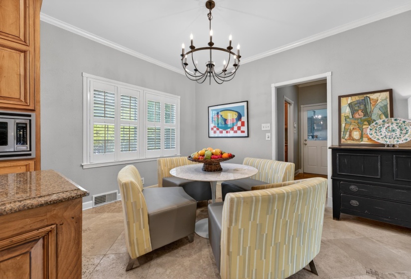 Breakfast nook featuring a round marble-look table, crown molding, and a chandelier
