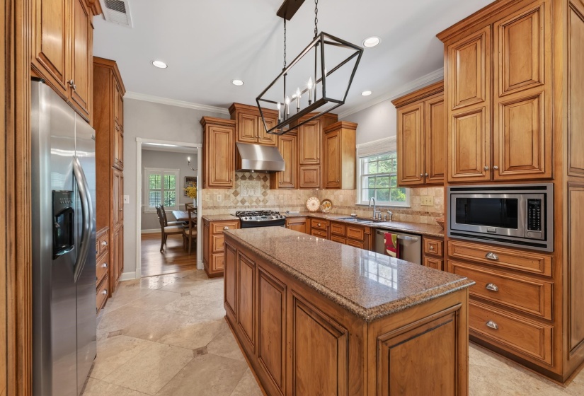 Kitchen featuring wood cabinetry, stainless steel appliances, a center island with a stone countertop, recessed lighting, and a decorative chandelier