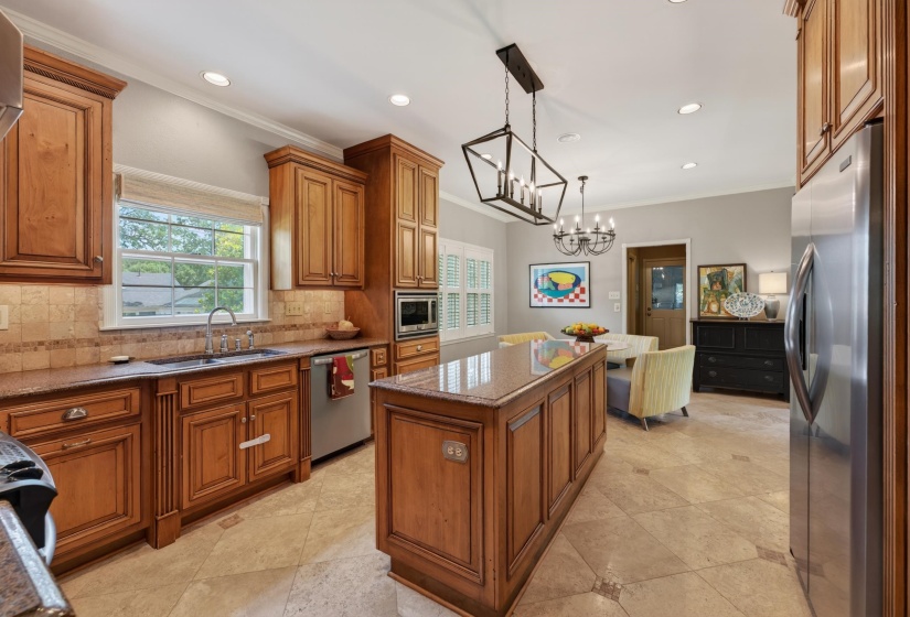 Kitchen featuring a central island with a granite countertop, wood-finish cabinetry, stainless steel appliances, tiled flooring, and recessed lighting