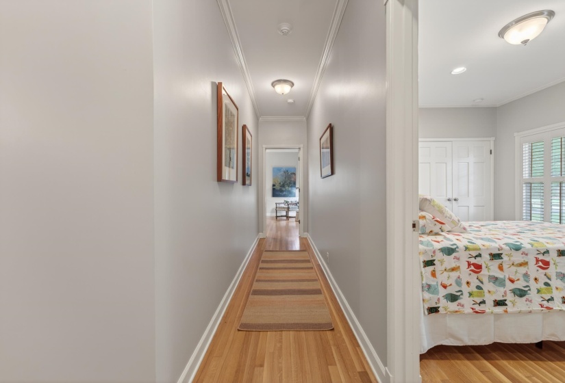 Hallway with wood-finish flooring, crown molding, and recessed lighting