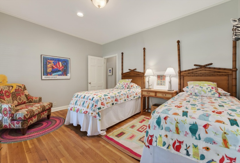 Bedroom featuring light gray wall paint, wood-finish flooring, a flush-mount ceiling light fixture, and crown molding
