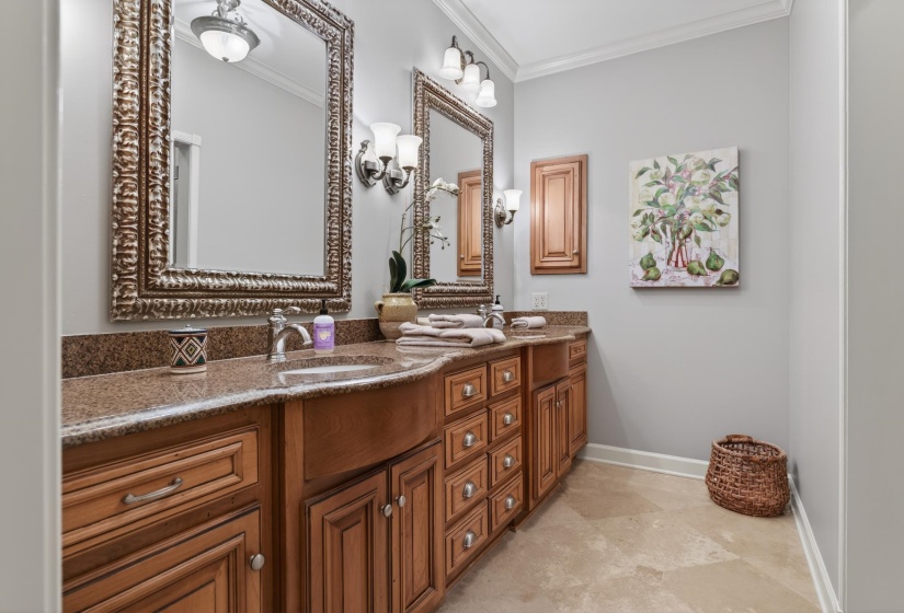 Double vanity with warm wood cabinetry, stone countertops, and integrated sinks