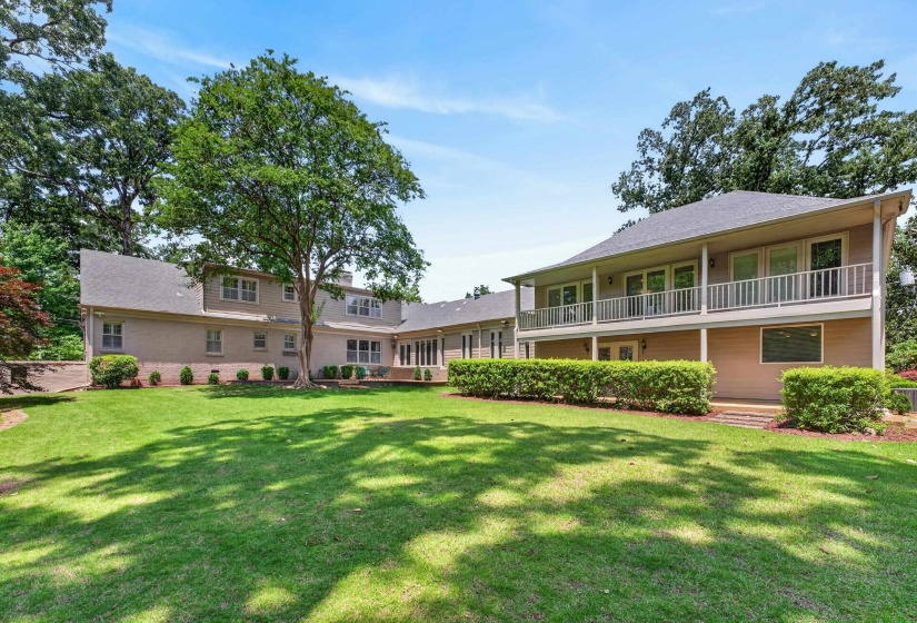 Expansive green lawn bordering a two-story residence with a full-width upper-level balcony