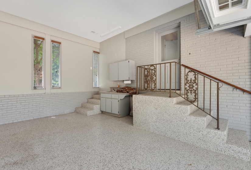 Finished garage space featuring light-colored speckled flooring, painted brick walls, and multiple windows