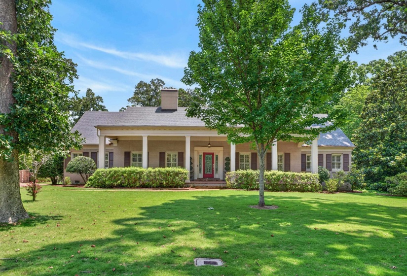 Expansive front lawn with mature trees and a long covered porch