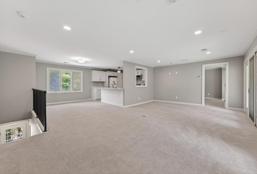 Spacious open-concept room featuring light-toned carpeting, recessed lighting, and a neutral wall color