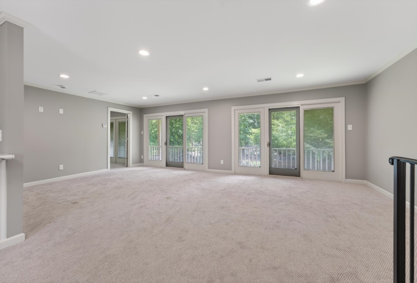 Expansive room featuring light gray walls, plush carpeting, recessed lighting, and white crown molding