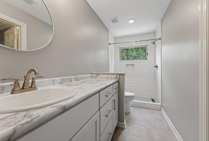 Bathroom featuring a vanity with a white-finish countertop, undermount sink, and brushed brass faucet