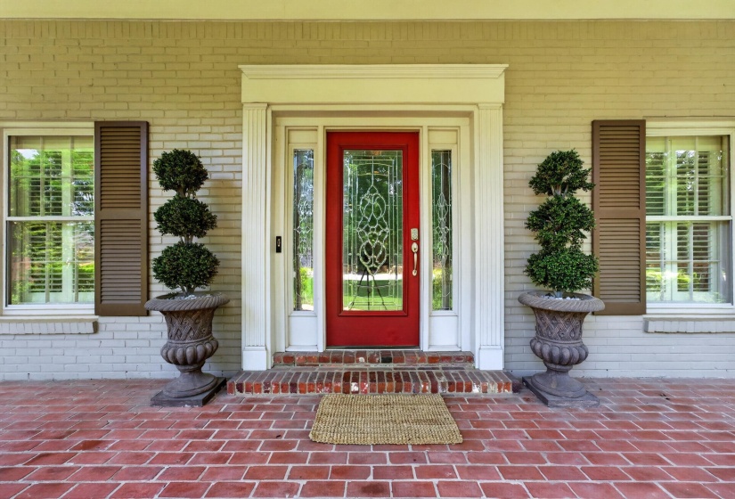 Red front door with decorative glass inserts framed by sidelights and a white surround