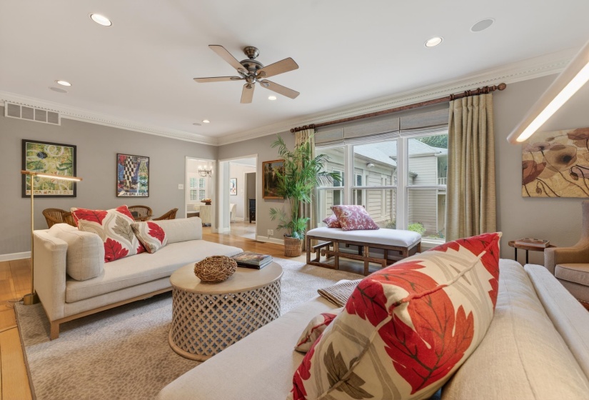 Living area featuring hardwood flooring, recessed lighting, crown molding, a ceiling fan, and large windows with privacy blinds