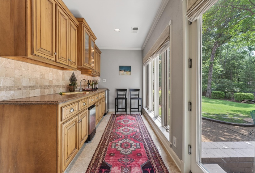 Kitchenette featuring wood cabinetry, stone-finish countertops, a built-in sink, and a beverage refrigerator