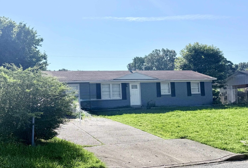 Single-story residence featuring a gray exterior with black window shutters and a white front door