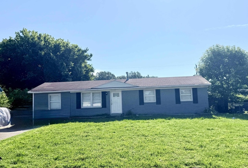 Ranch-style exterior featuring a combination of horizontal siding and painted brick, a brown shingled roof, a white front door, and black window shutters