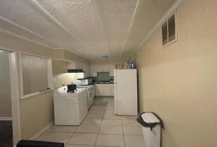 Kitchen featuring white cabinetry, tile backsplash, and tile flooring
