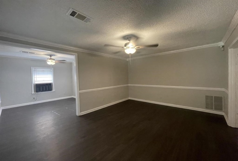 Spacious interior room with dark wood-finish flooring, light neutral wall color, and white crown molding