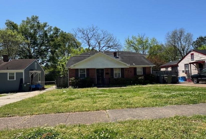 View of front of home featuring brick siding, a front lawn, fence, and an outbuilding