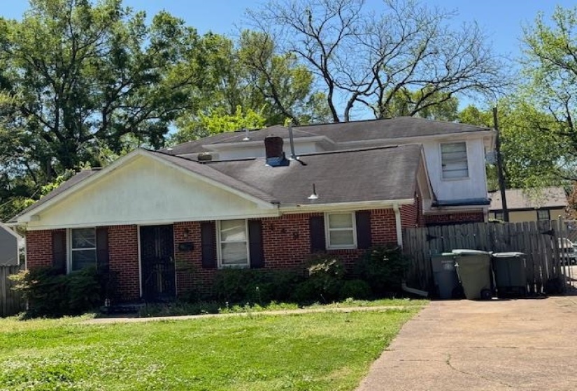View of front of house featuring brick siding, fence, and a front lawn