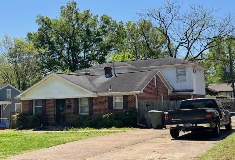 View of front of house with brick siding, a front lawn, fence, and concrete driveway