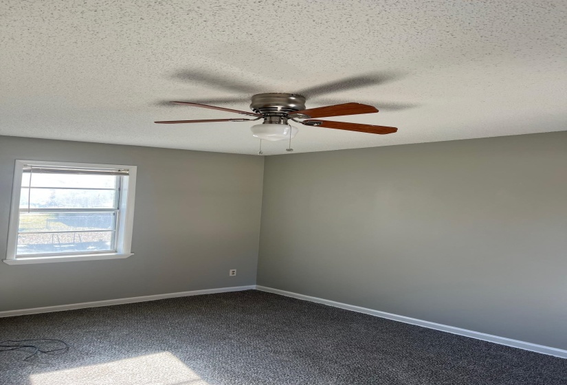 Spare room with baseboards, dark carpet, a textured ceiling, and ceiling fan