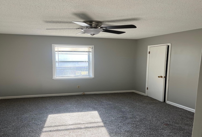 Carpeted spare room featuring a ceiling fan, baseboards, and a textured ceiling
