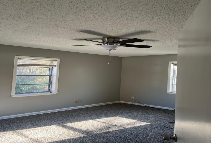 Carpeted empty room with baseboards, a wealth of natural light, a textured ceiling, and ceiling fan