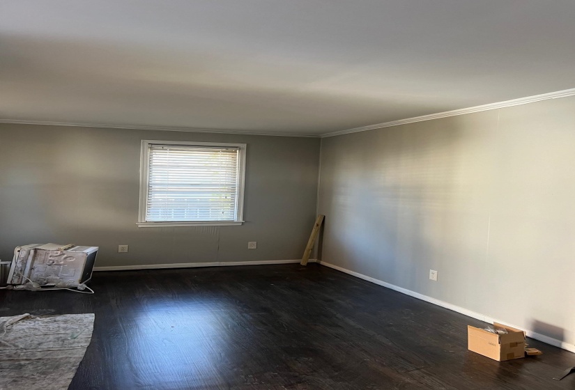 Spare room featuring baseboards, crown molding, and wood finished floors