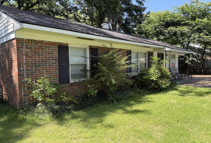 Brick exterior featuring dark shutters and a covered entry