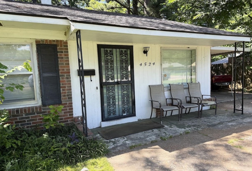 Brick and white siding exterior featuring a covered entry, security screen door, and a single-car carport