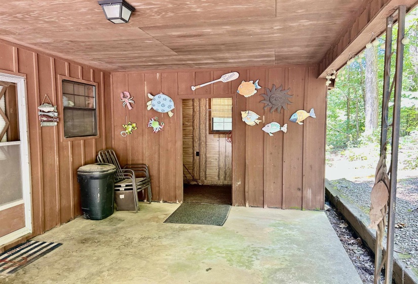 Covered outdoor patio with exposed wood-finish ceiling, vertical wood-finish siding, and a concrete slab floor