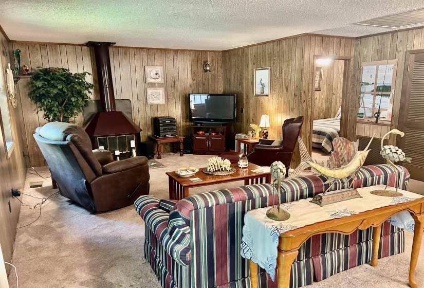 Living area featuring wood paneling and a freestanding corner fireplace