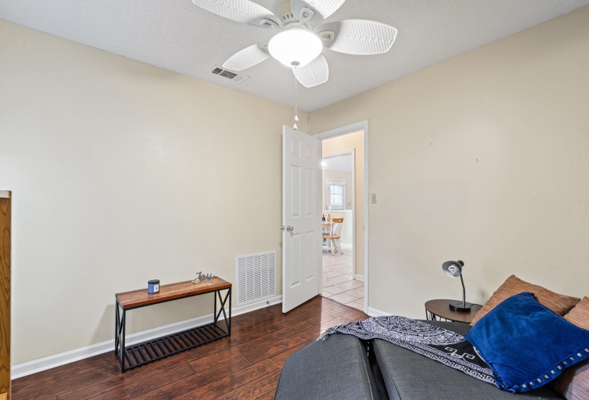 Room featuring wood-finish flooring, a ceiling fan with integrated lighting, and a white interior door