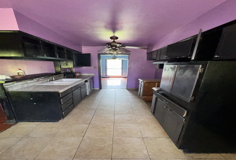 Galley kitchen featuring ceramic tile flooring, dark cabinetry, and light-toned countertops