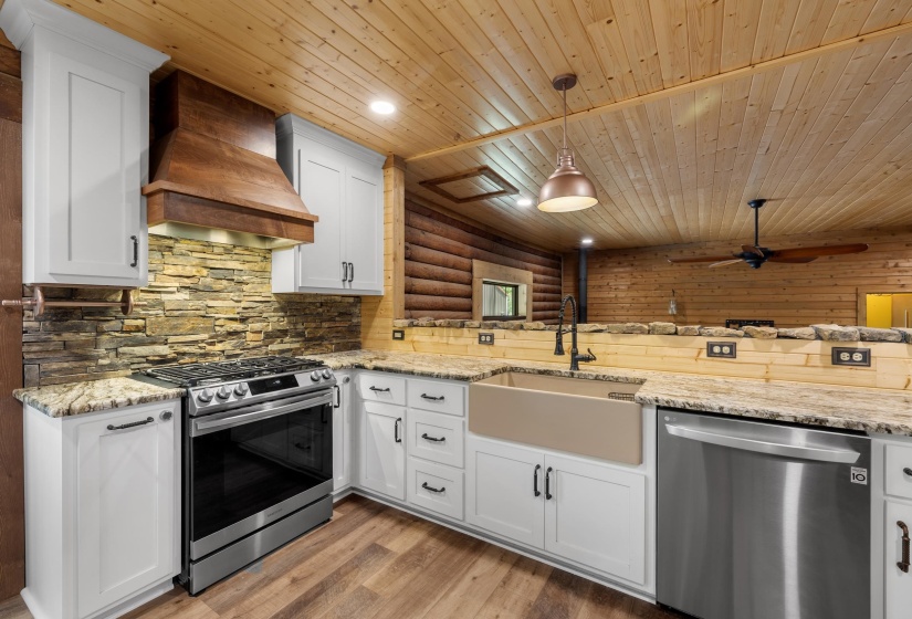 Kitchen featuring white cabinetry, stone veneer backsplash, wood-finish flooring, and granite countertops