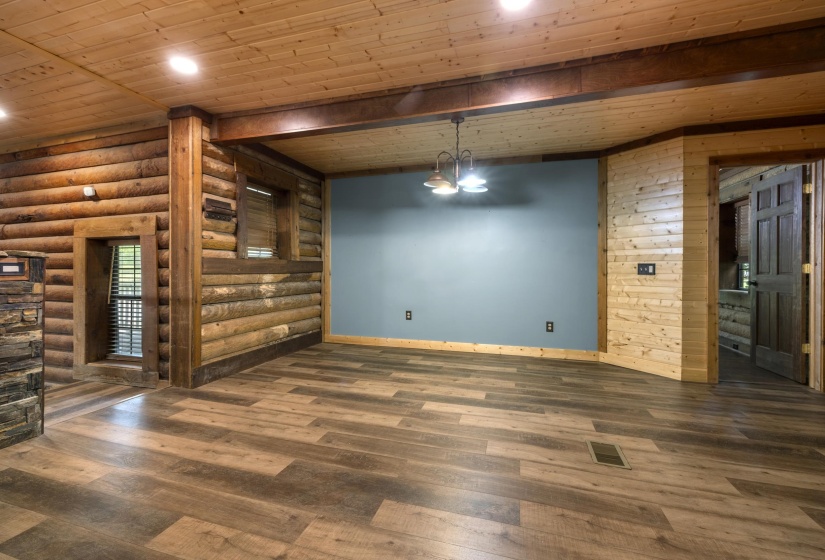 Spacious interior featuring wood-finish flooring, log walls, wood plank ceiling, and a prominent wood beam