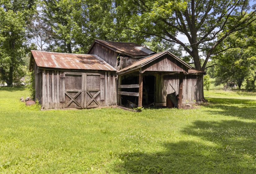 Rustic wooden outbuilding featuring a corrugated metal roof and barn-style doors