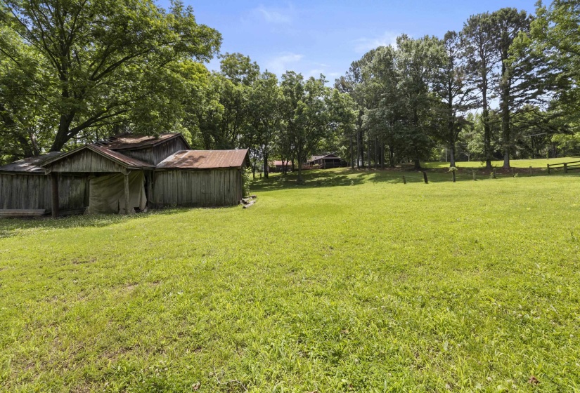 Expansive green space with an outbuilding featuring distressed wood siding and a corrugated metal roof